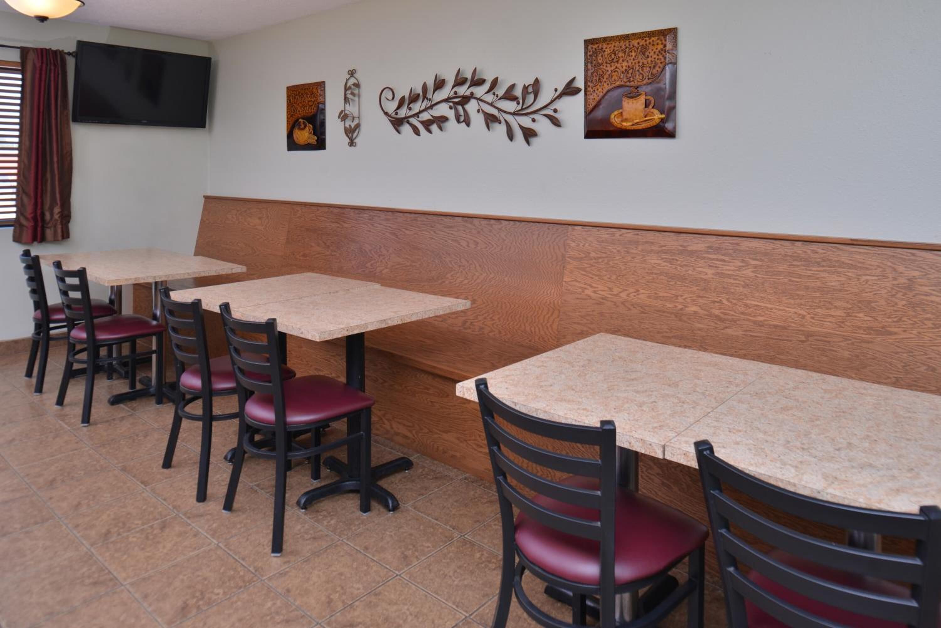 Un restaurant avec plusieurs tables et chaises, un banc en bois et des œuvres d’art murales.