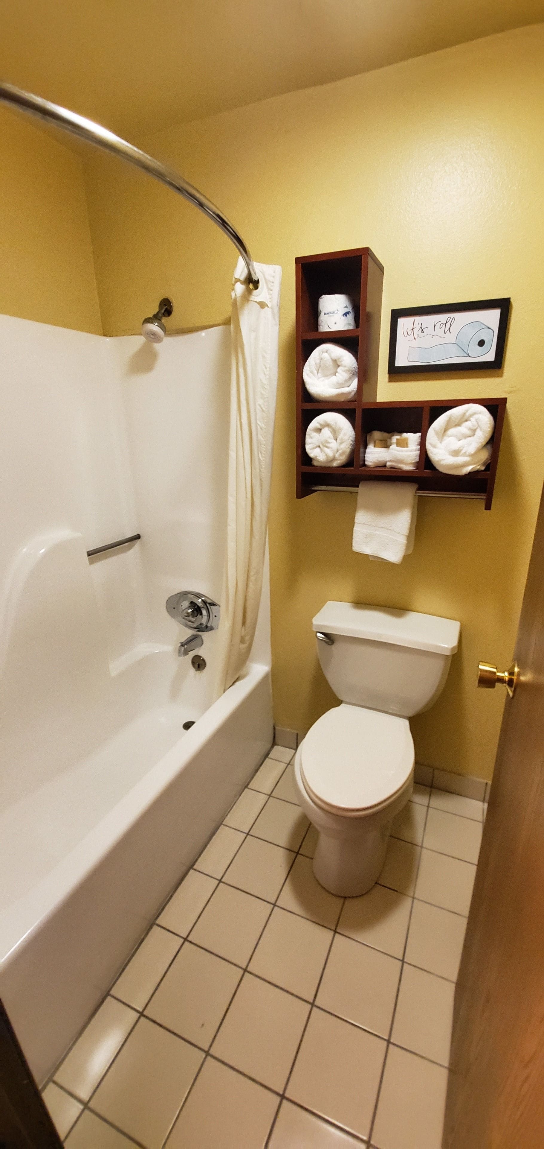 Une salle de bain avec une baignoire, des toilettes et une étagère avec des serviettes.