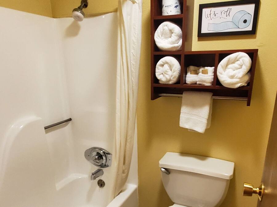 Une salle de bain avec une baignoire, des toilettes et une étagère avec des serviettes.