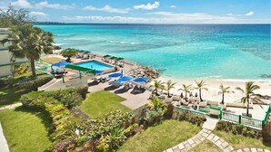 Un resort con piscina, sillas de descanso y vista al océano.