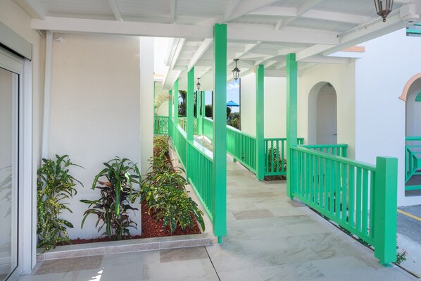 A covered walkway with green railings and potted plants. - Rostrevor Hotel (St. Lawrence Gap)