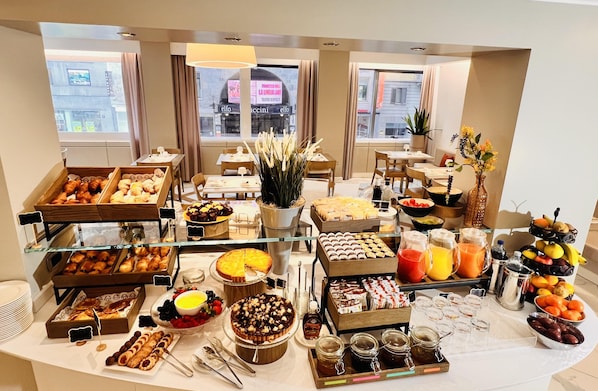 Un bufé con diversos alimentos, una estación de café y una presentación de frutas.