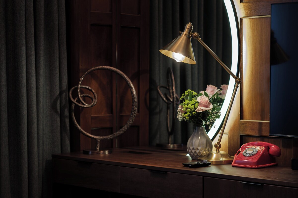 A desk with a vintage telephone, a desk lamp, and a vase with flowers.