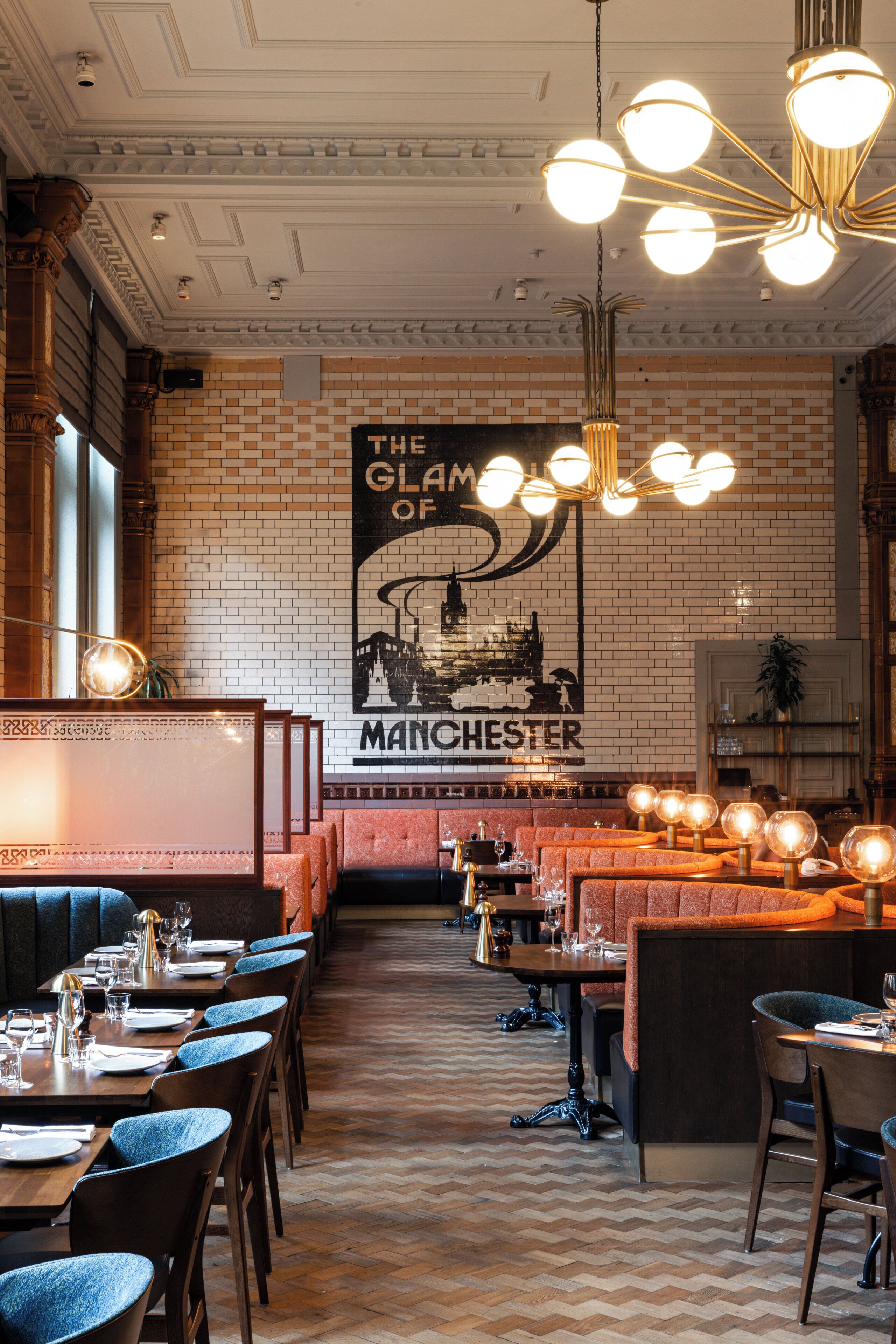A restaurant with brick walls, a large poster of Manchester, and multiple dining tables and chairs.