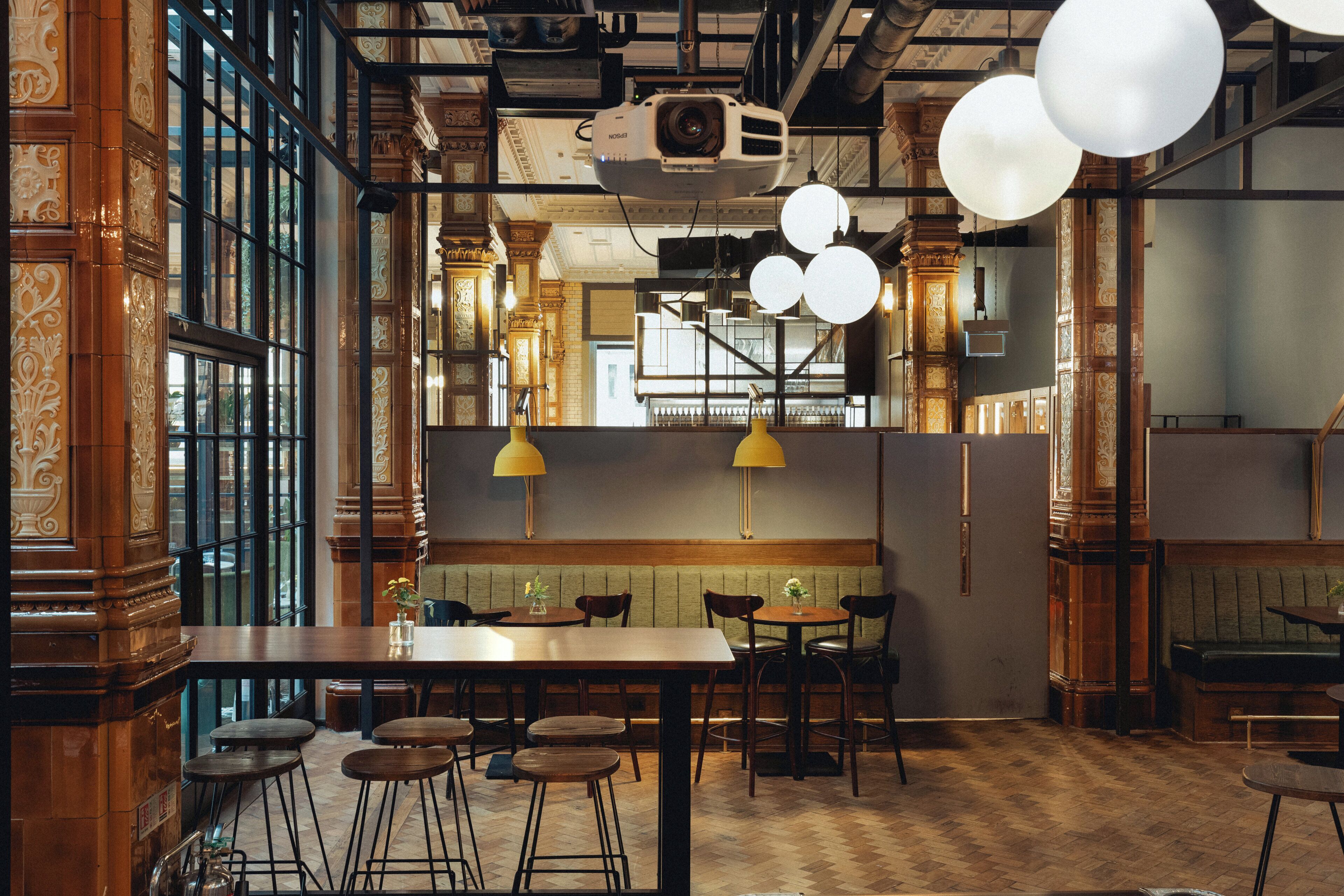 A restaurant interior with wooden decor, large windows, and hanging spherical lights.