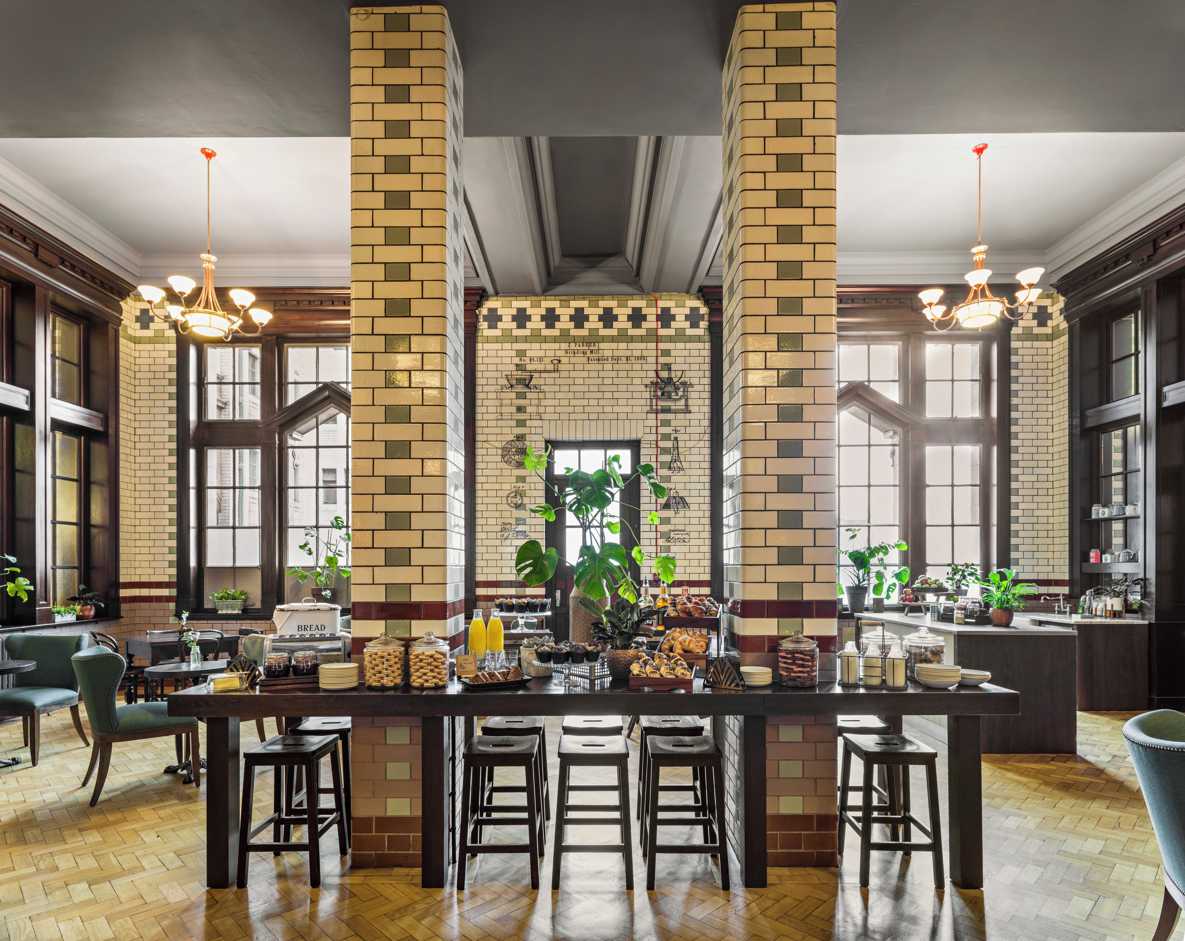 A spacious bar area with high ceilings, large windows, and a central brick column.