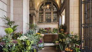 Passadís amb plantes en testos i flors, parets de pedra i un taulell de fusta.