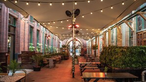 An indoor patio area with string lights, wooden tables, and potted plants. - Kimpton Clocktower by IHG (Manchester)