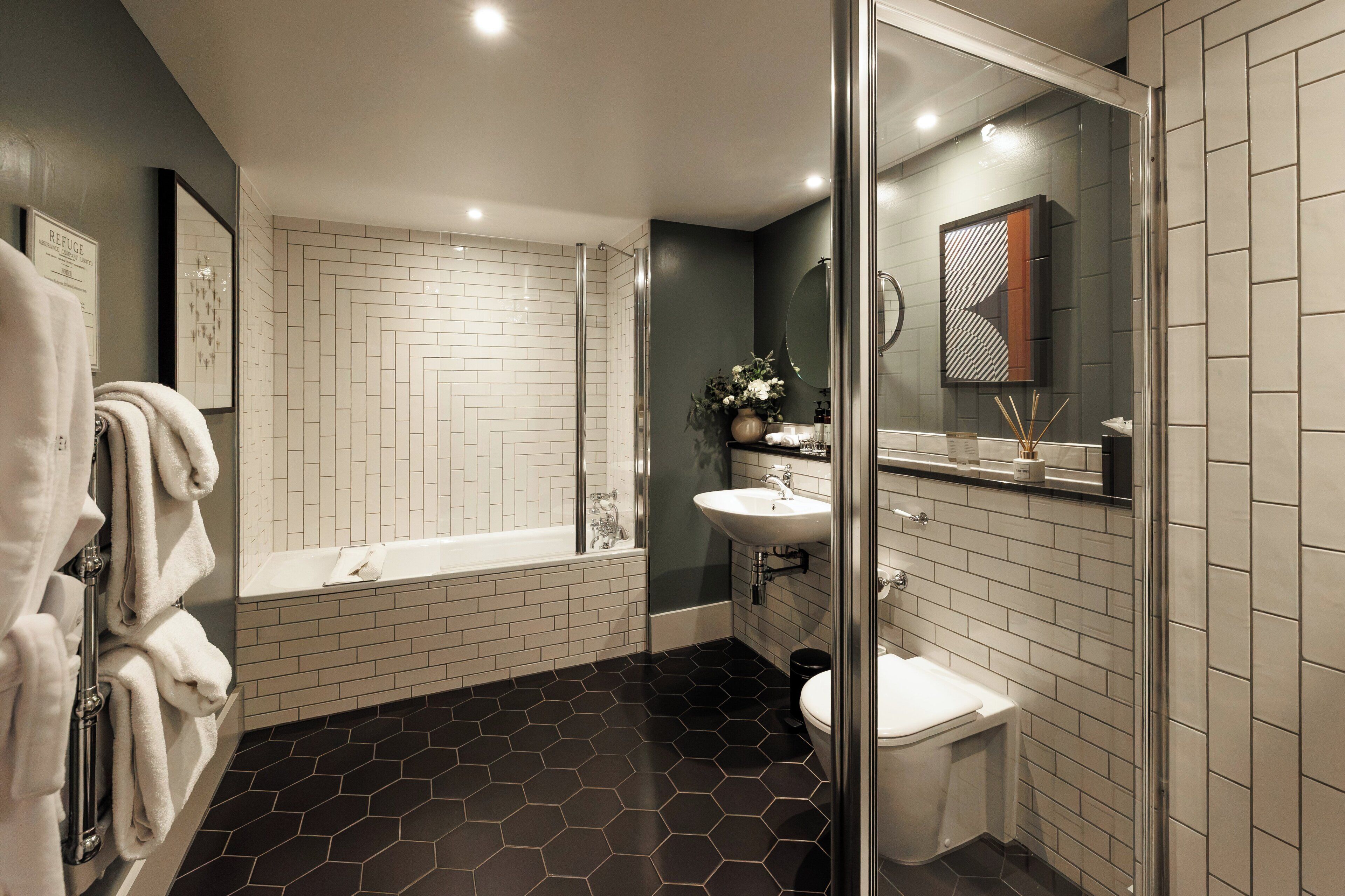 A modern bathroom with a glass-enclosed shower, a white bathtub, and a sink with a mirror above it.