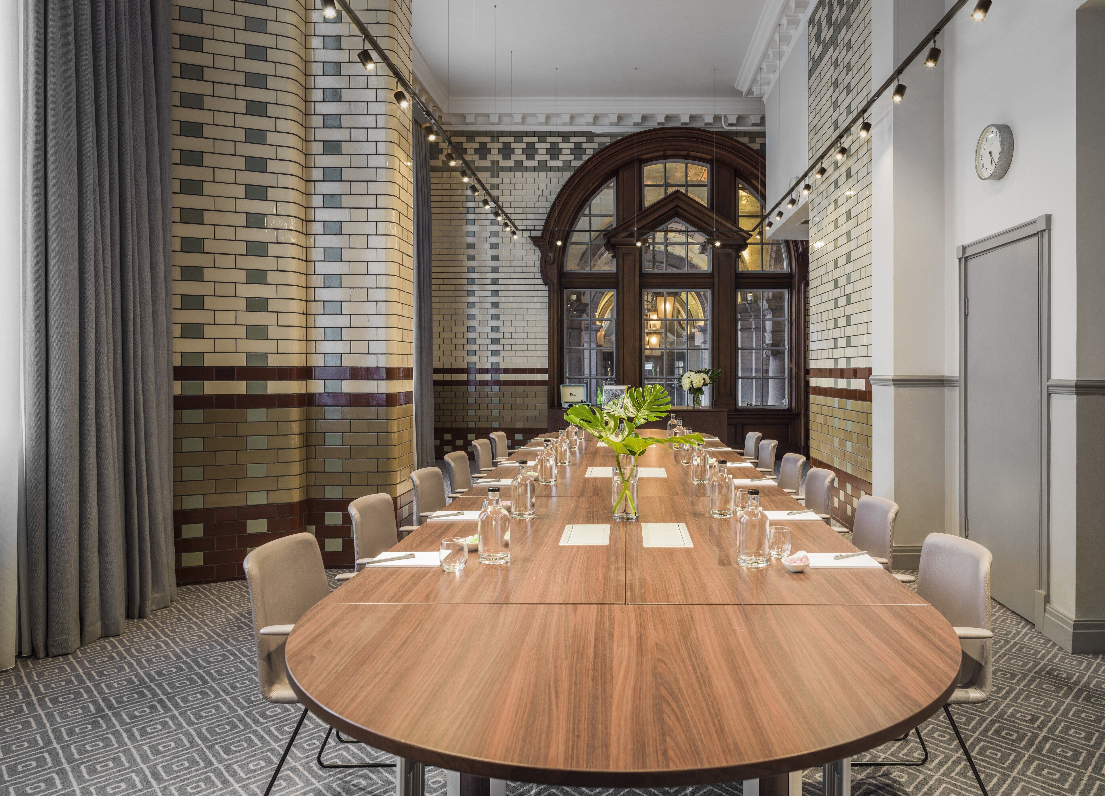 Een vergaderzaal met een lange houten tafel, stoelen en een decoratieve plantenpresentatie.