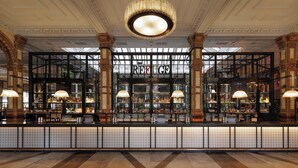 A bar area with a 'REFUGE' sign, large columns, and a chandelier. - Kimpton Clocktower by IHG (Manchester)