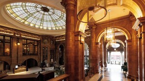 A grand lobby with a large glass dome ceiling, ornate columns, and a reception desk. - Kimpton Clocktower by IHG (Manchester)