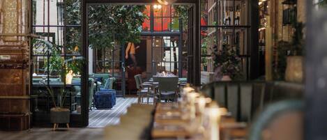 Un restaurant avec une longue table, des chaises et des plantes en pot.