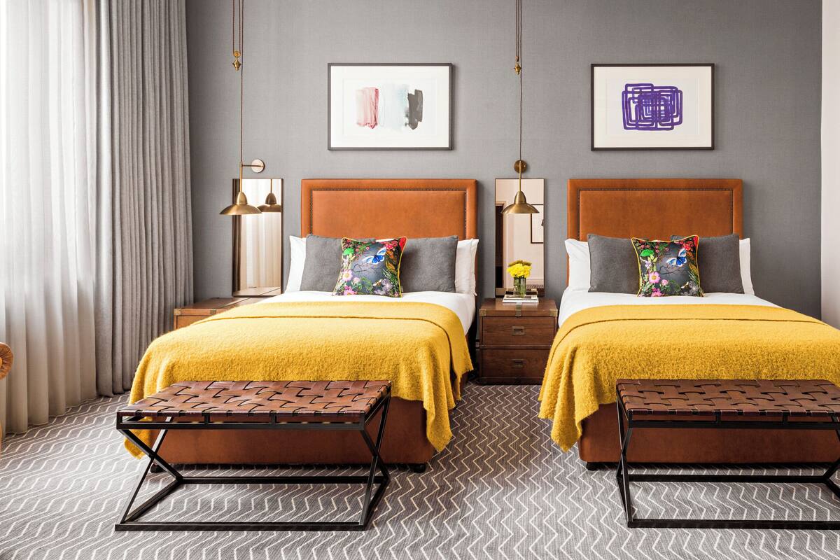 A hotel room with two beds, a sofa, and a mirror.