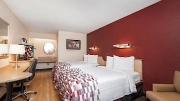 A hotel room with a bed, a desk, a chair, a TV, and a mirror.