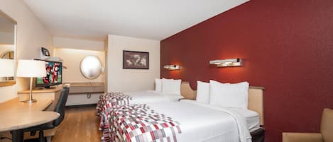 Une chambre d’hôtel avec un lit, un bureau, une chaise, une télévision et un miroir.