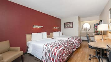 A hotel room with two beds, a desk, a chair, and a television.