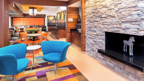 A hotel lobby with a stone wall, a fireplace, and a colorful carpet. - Fairfield Inn & Suites Galesburg (Galesburg)