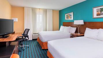 A hotel room with two beds, a desk with a computer, a TV, and a chair.