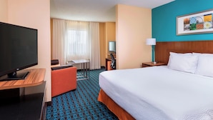 A hotel room with a bed, a TV, a desk, a chair, and a window with curtains. - Fairfield Inn & Suites Galesburg (Galesburg)