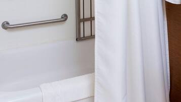 A bathroom with a white bathtub, a metal grab bar, and a white shower curtain.