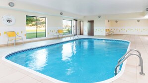 An indoor swimming pool with clear glass walls, yellow chairs, and a tiled floor. - Fairfield Inn & Suites Galesburg (Galesburg)