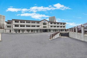 A multi-story building with a central entrance, a parking lot in front, and a clear sky. - Motel 6 Atlanta, GA - Downtown (Atlanta)