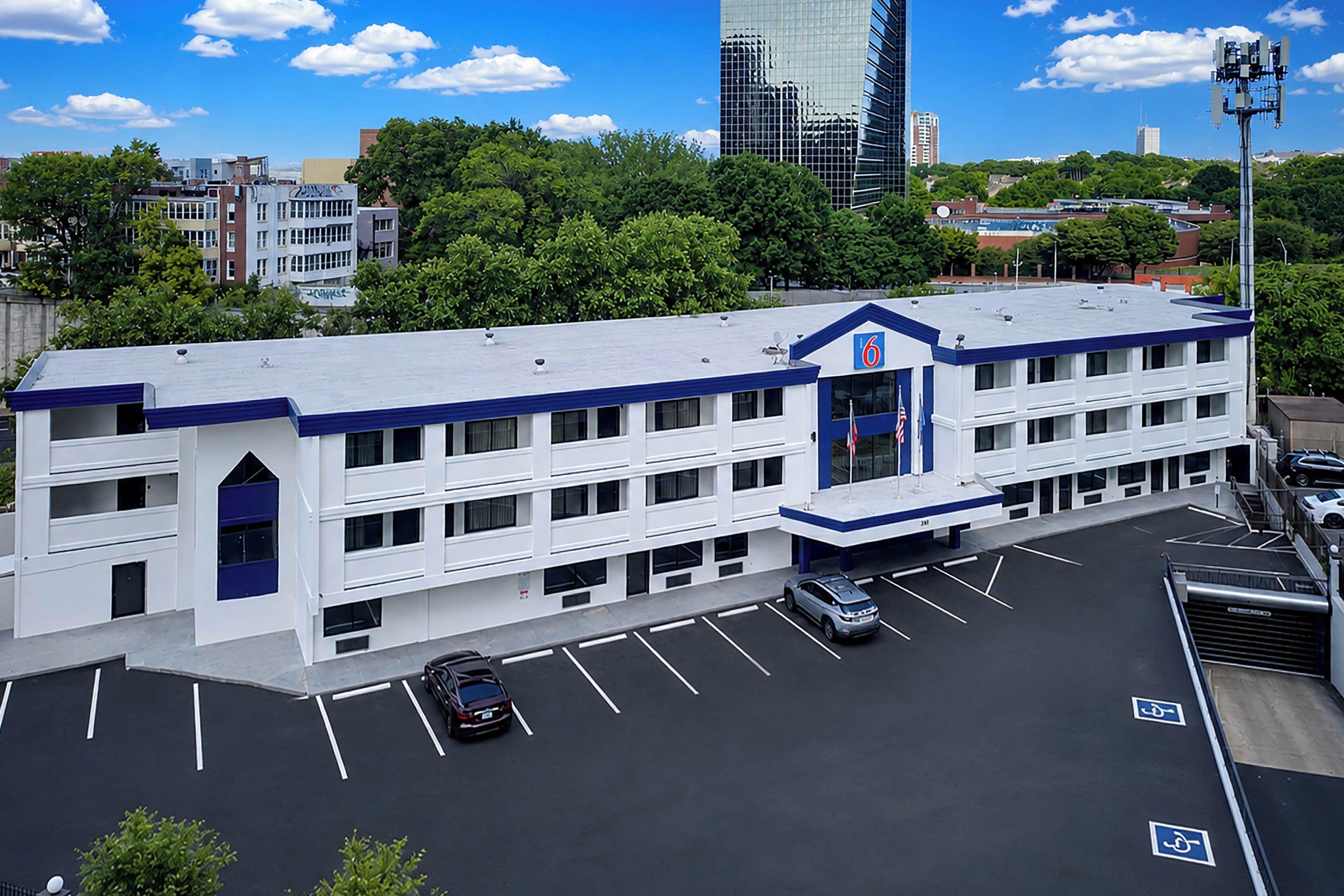 A multi-story building with a flat roof, a parking lot with marked spaces, and a clear view of the surrounding urban landscape.