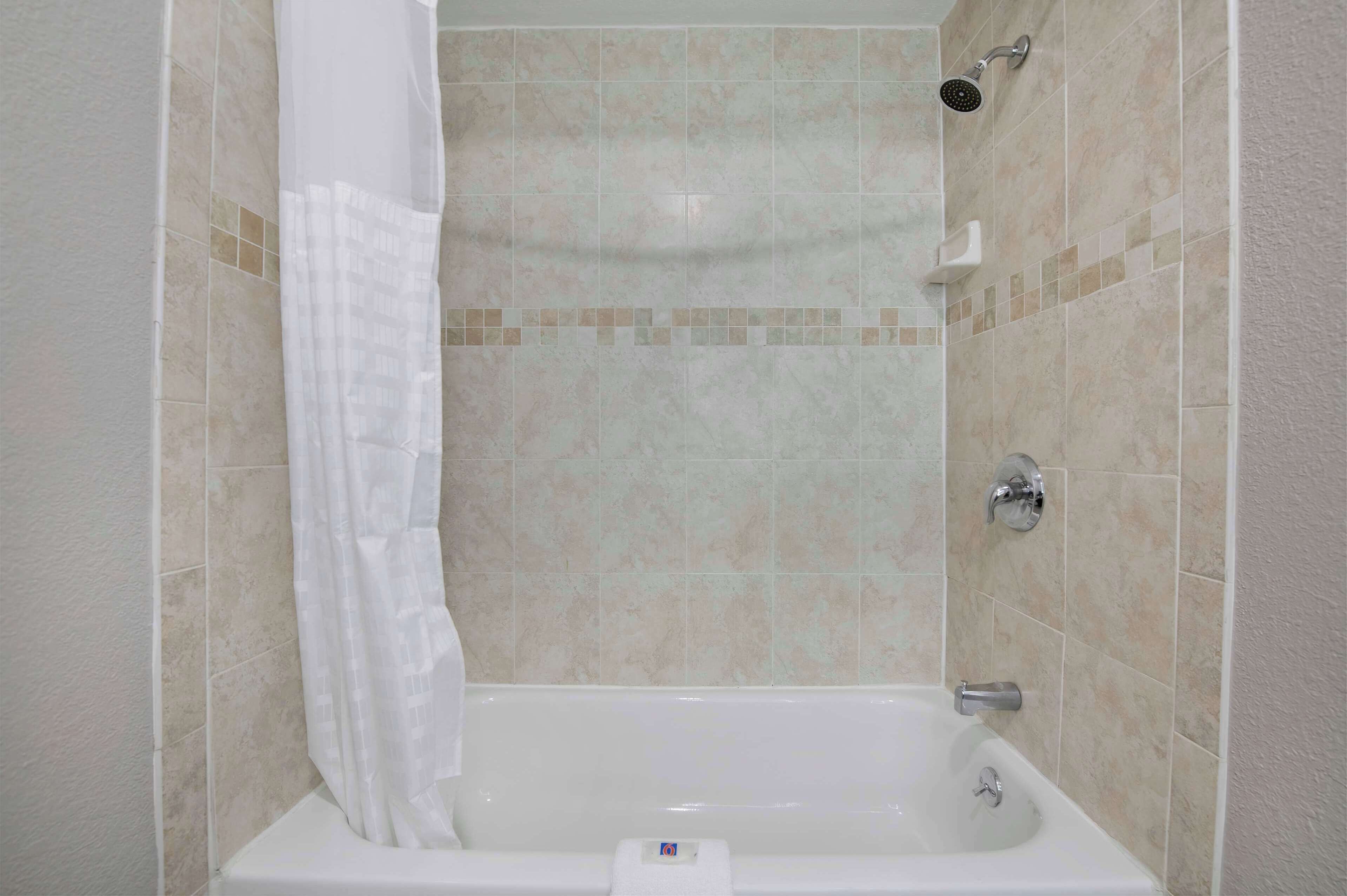 Ein Badezimmer mit Badewanne, Dusche und gefliesten Wänden.