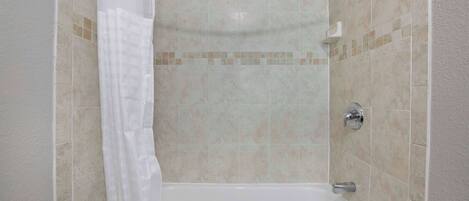A bathroom with a bathtub, shower, and tiled walls.