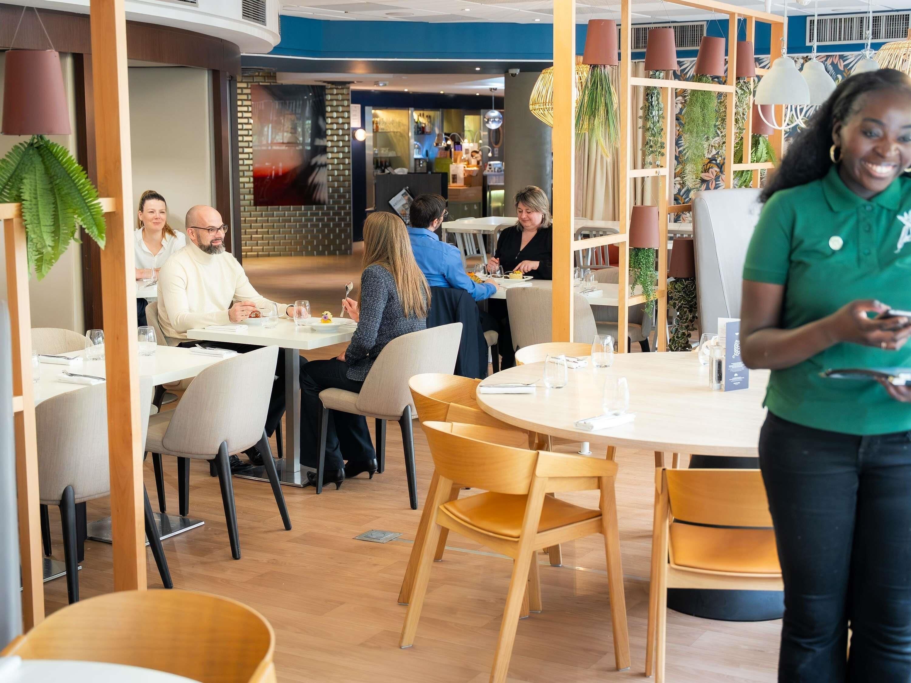 A restaurant with round tables, chairs, and a waiter.