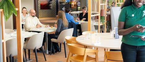 A restaurant with round tables, chairs, and a waiter.