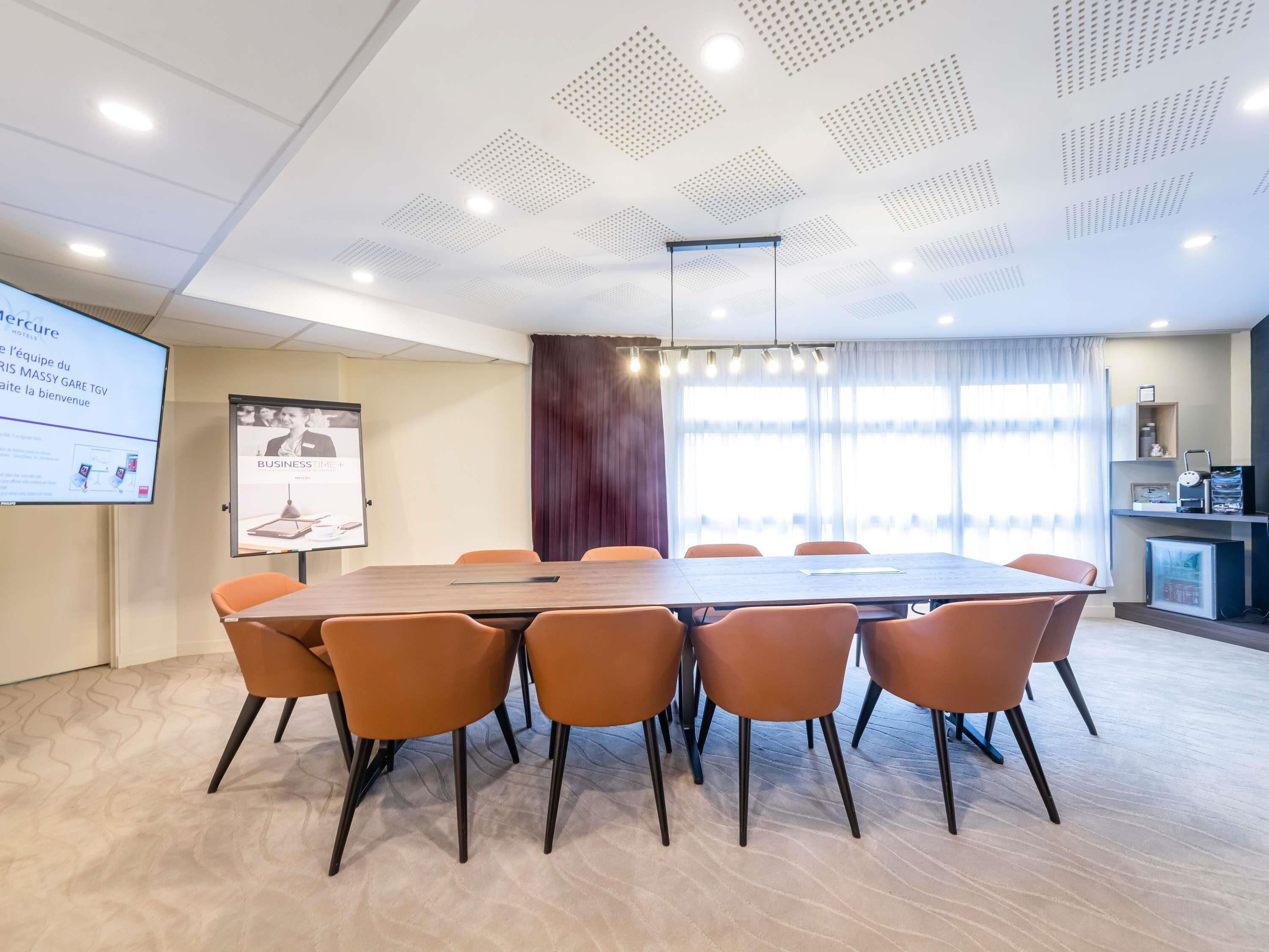 A conference room with a large table, orange chairs, a projector screen, and a presentation on the wall.