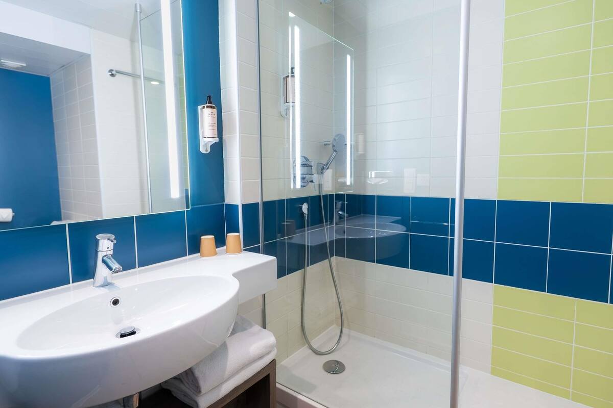 A bathroom with a white sink, a glass-enclosed shower, and blue and white tiled walls.
