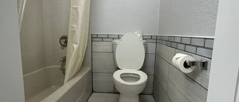 Un baño pequeño y moderno con bañera, inodoro y cortina de ducha.
