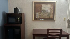 A small kitchenette with a microwave, a wooden table, and a chair. - Key Inn Roseville (Roseville)