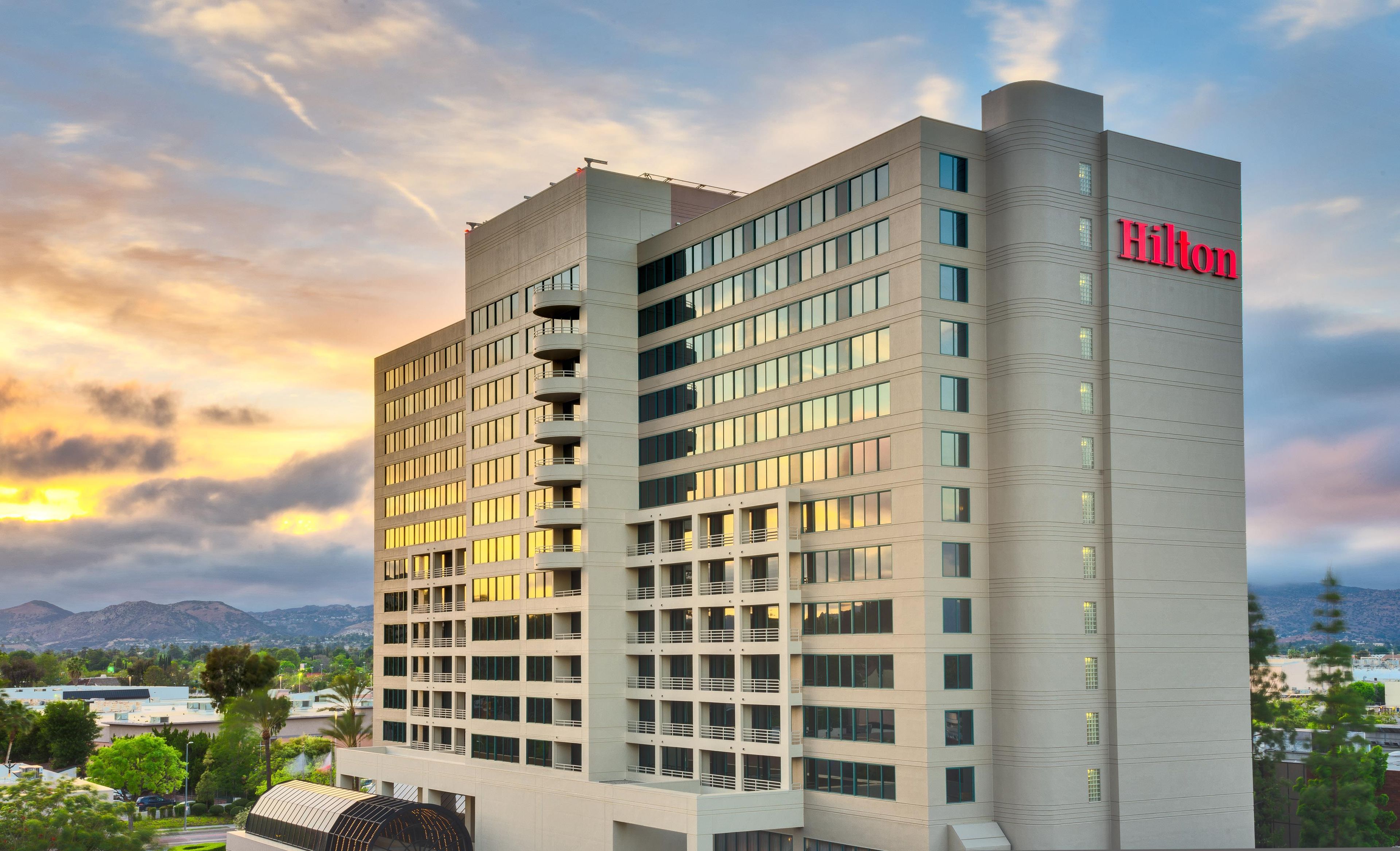 A modern hotel building with multiple floors, large windows, and a prominent 'Hilton' sign.