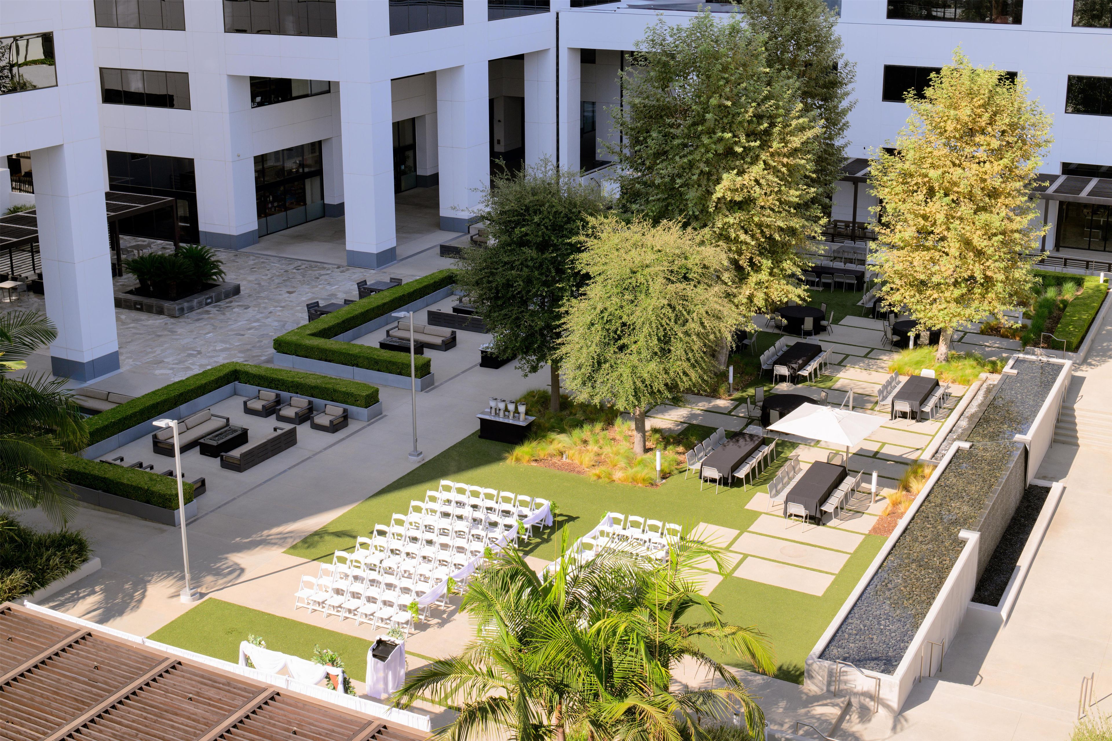 Une cour avec des espaces de repos en plein air, une scène et un bâtiment doté de grandes fenêtres.