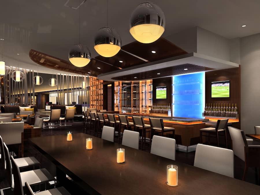A modern bar area with multiple seating options, including bar stools and tables, and a variety of lighting fixtures.