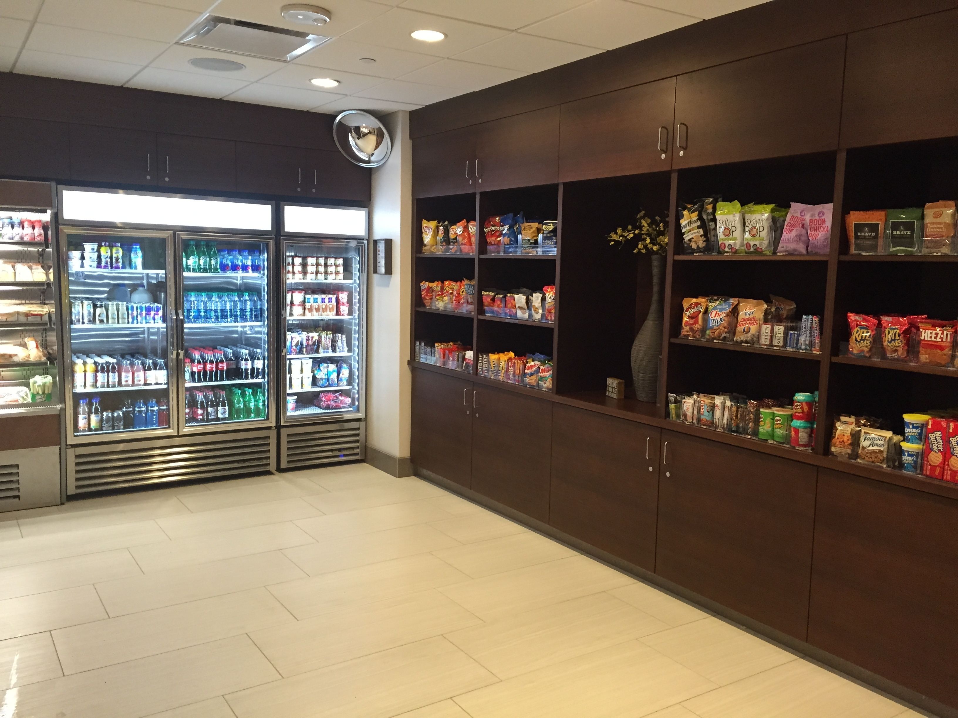 A grocery store interior with refrigerated beverage cases and shelves stocked with snacks and packaged goods.