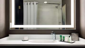 A modern bathroom with a large mirror, a white sink, and a shower area.