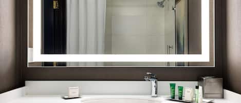 Un baño moderno con un espejo grande, un lavabo blanco y una zona de ducha.