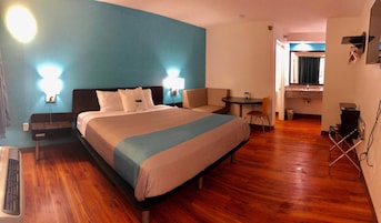 A hotel room with a large bed, bedside tables, a desk, and a chair.