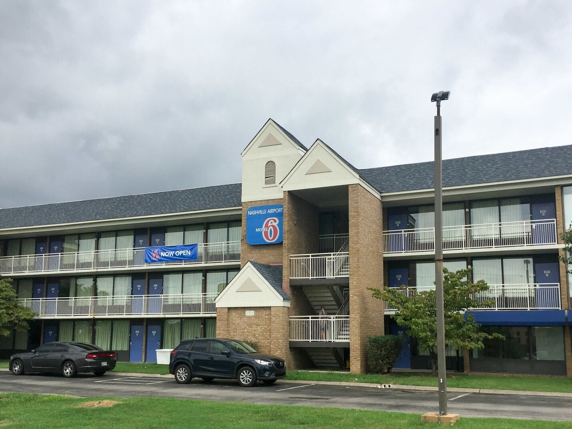 A motel with a sign indicating it is now open, located near an airport.
