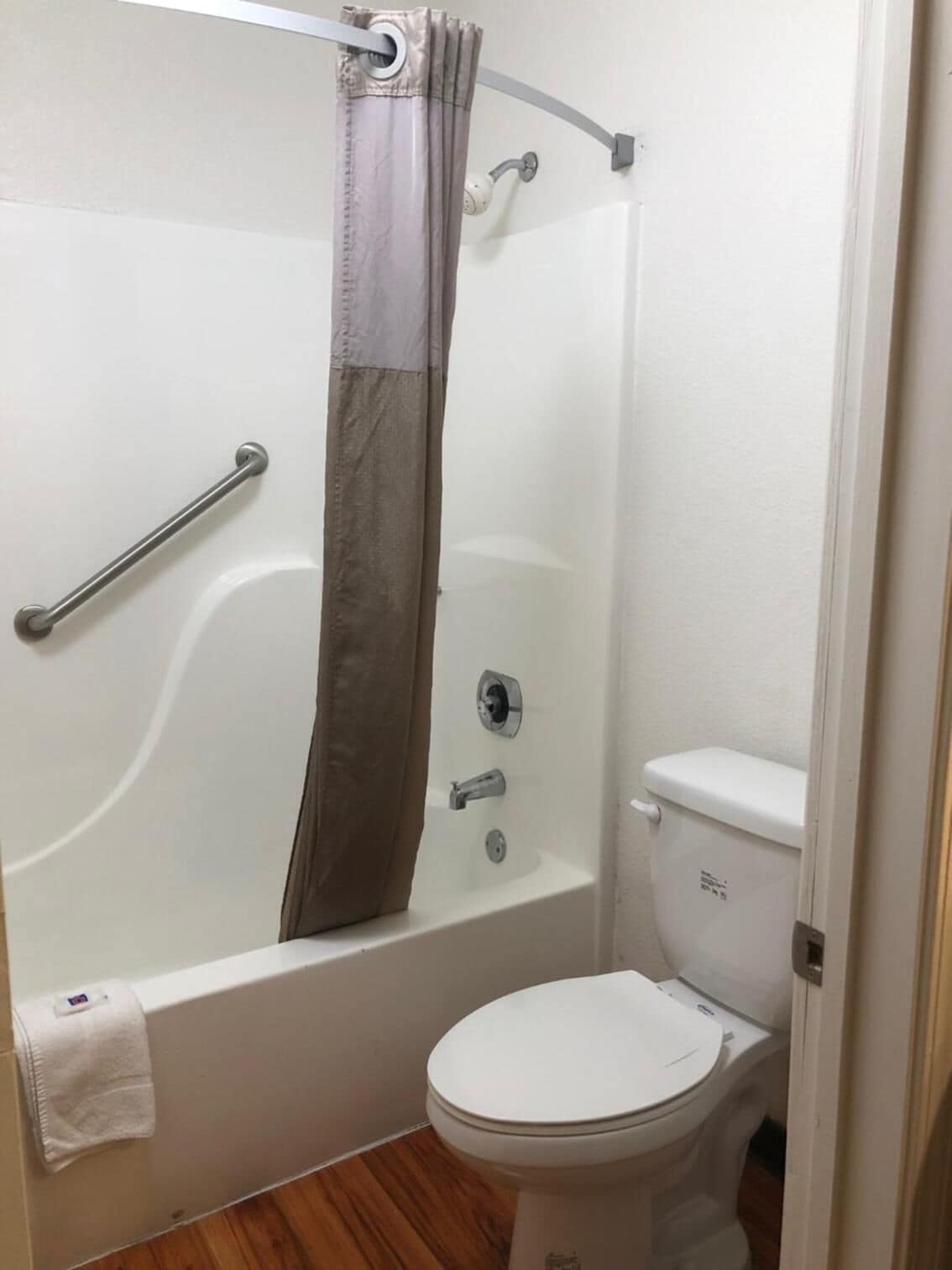 A bathroom with a shower, toilet, and grab bar.