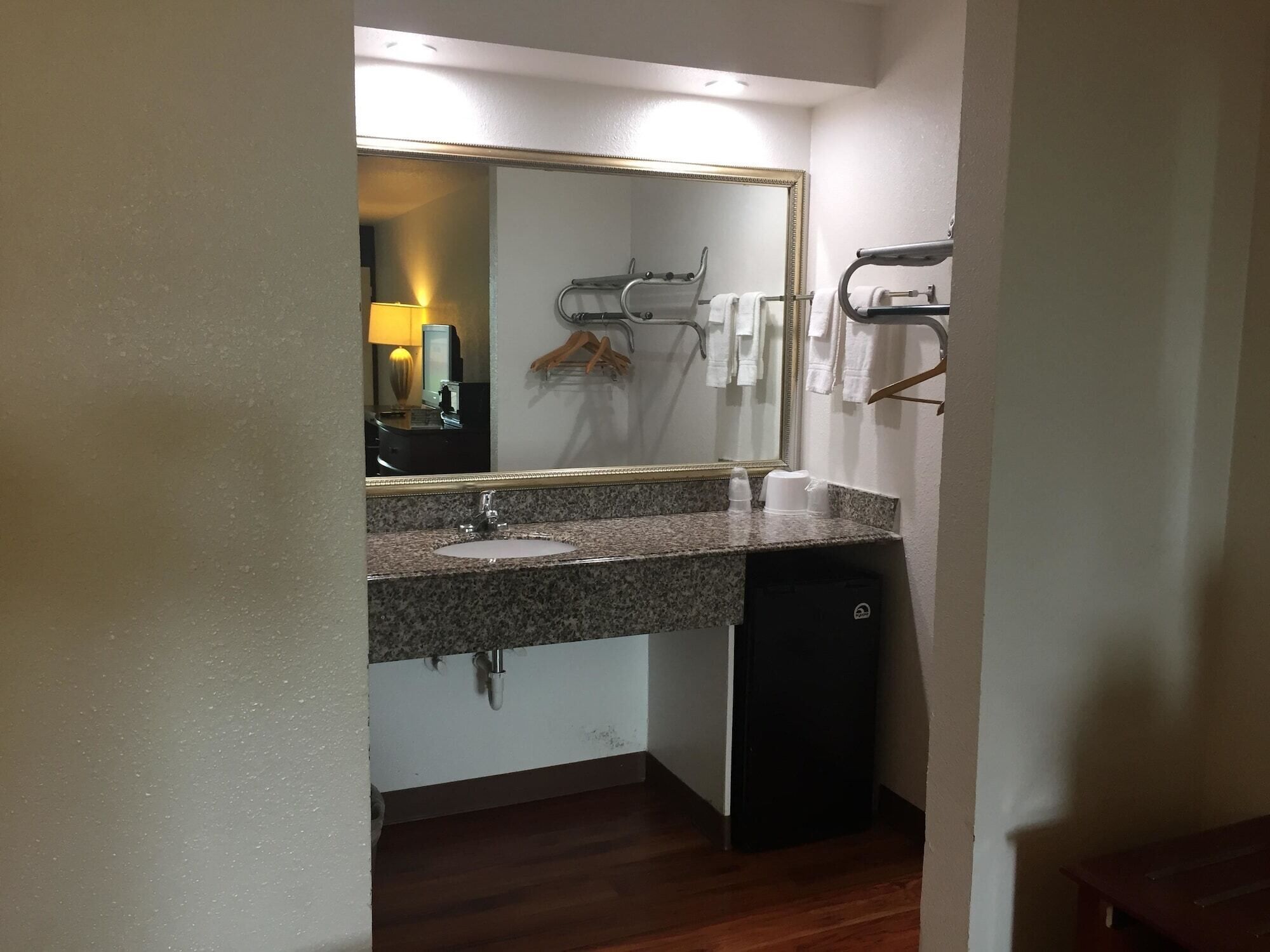 A bathroom with a granite countertop sink, a mirror, a towel rack, and a black cabinet.