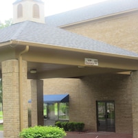 A building with a low clearance sign, brick walls, and a covered entrance.