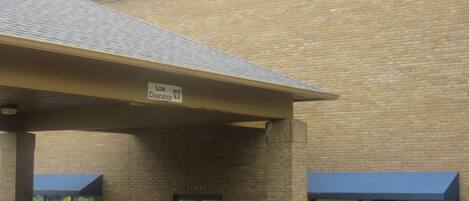 A building with a brick facade, a covered entrance, and a sign indicating low clearance.