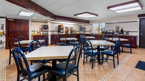 Ein Restaurant mit mehreren Tischen, Stühlen, einer Küchenzeile und einem Fliesenboden.