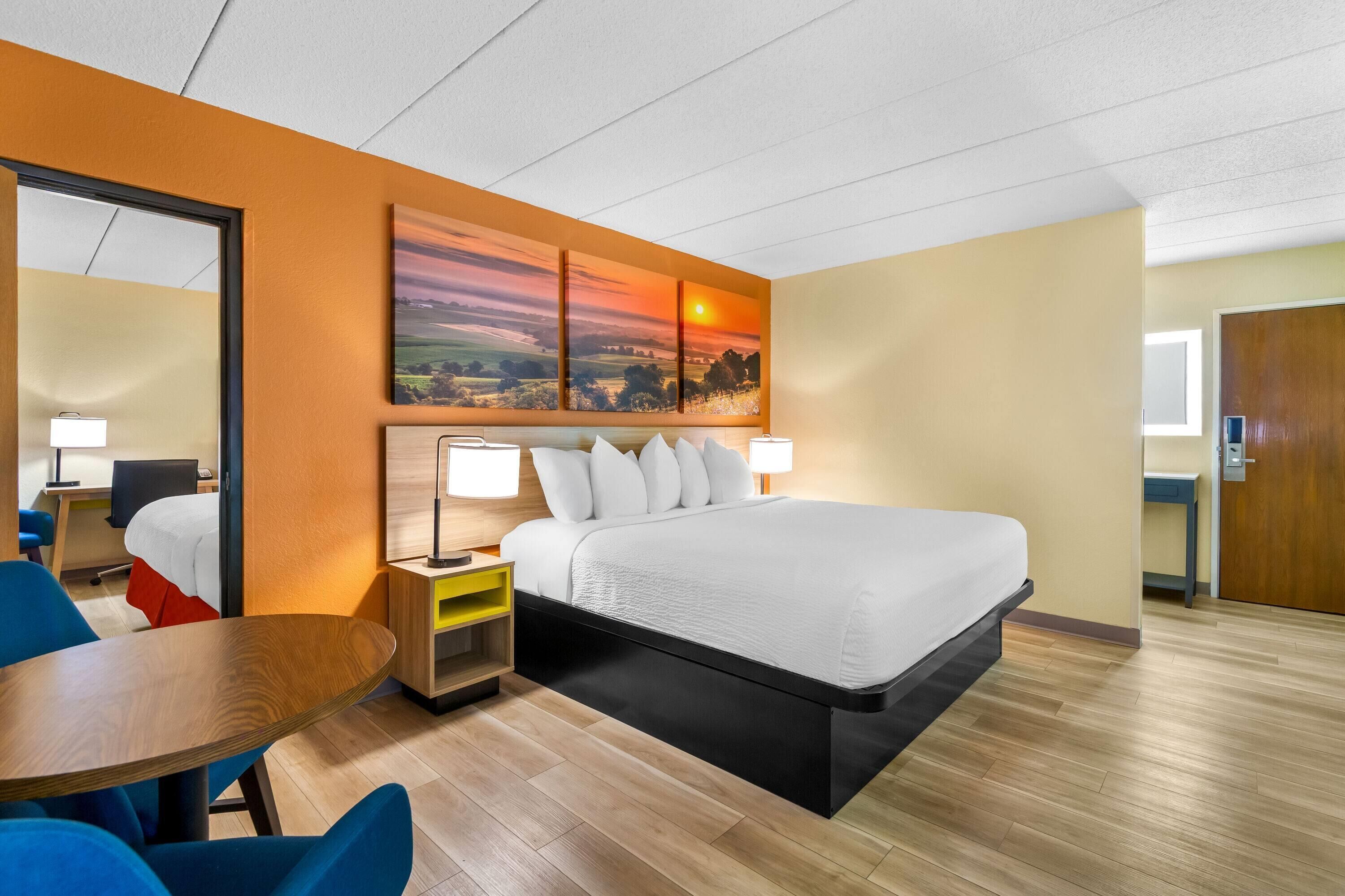 Een hotelkamer met een bed, nachtkastjes, een bureau en een stoel.